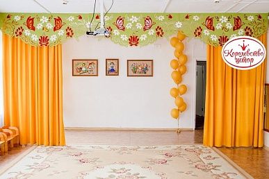 Красивые шторы оранжевого цвета с бабочками и цветами в музыкальный зал детского сада.